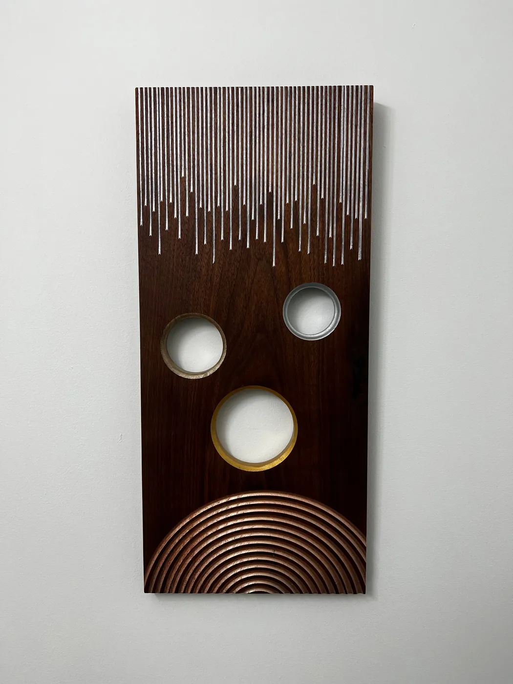 Vertical wood wall art with circular openings and carved line detail