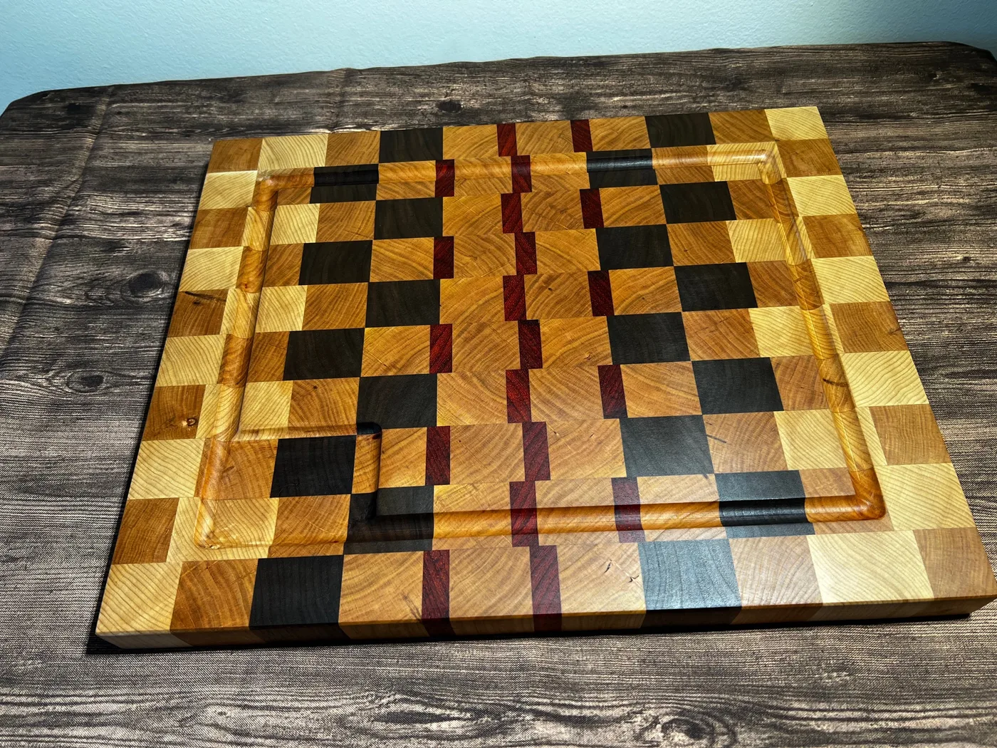 End-grain cutting board with mixed hardwood blocks and a red accent strip